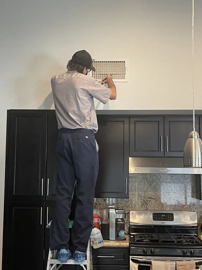 Technician inspecting an air vent during HVAC service in Revere